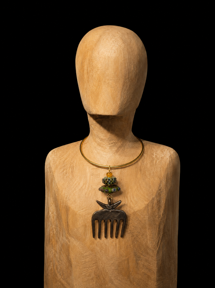 Objet du quotidien, symbole de beauté et de dignité, ce peigne Akan du Ghana devient le point d'ancrage de ce collier ras-de-cou. Surmonté de deux perles de verre de Murano aux teintes inspirées de la nature, il révèle toute la noblesse de ses lignes épurées.