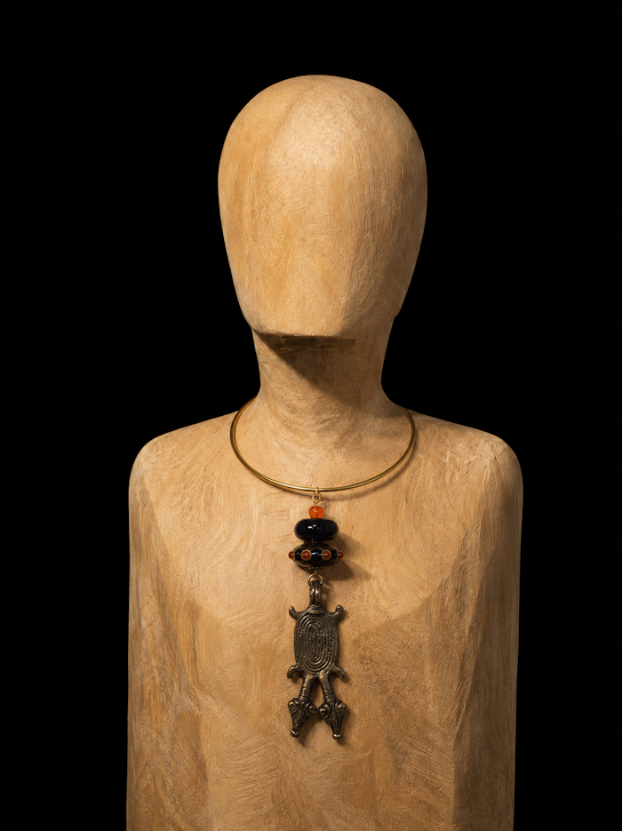 Au cœur de ce collier ras de cou, un pendentif Gan, Burkina Faso, en forme de reptile, semble suspendu dans le temps. Son bronze patiné, dialogue avec les reflets lumineux des perles de verre de Murano orange et indigo.
